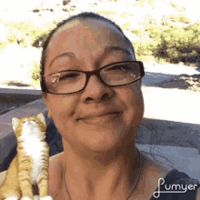 a woman wearing glasses is holding a cat in her arms