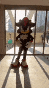 a person dressed as shadow the hedgehog is standing in front of a sliding glass door .