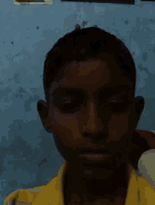 a young boy wearing a yellow shirt is making a peace sign with his hands