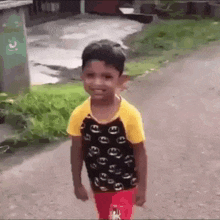 a young boy is walking down a street wearing a yellow and black shirt .