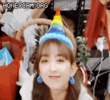 a woman wearing a rainbow hat and blue earrings is making a funny face .