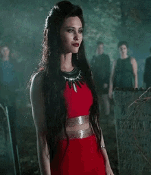 a woman in a red dress is standing in front of a cemetery .