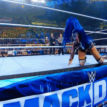 a woman with blue hair is in a wrestling ring with a sign that says mack d