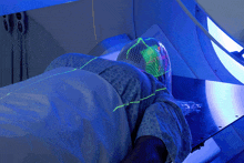 a person in a hospital gown is laying in a bed with a blue light shining on their head