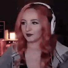 a woman with red hair is wearing headphones and making a face .