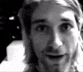 a close up of a man 's face with long hair and a beard in a black and white photo .