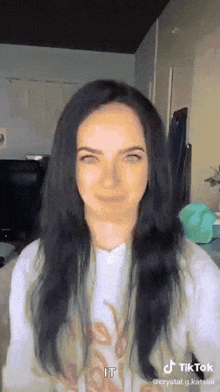 a woman with long black hair is making a funny face in a tik tok video .
