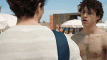 a shirtless man is talking to another shirtless man
