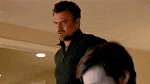 a man with a beard wearing a black sweater is standing next to another man .