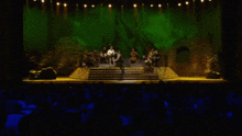 a group of people on stage with a green background