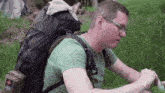 a man in a green shirt is sitting in the grass with a large backpack on his back