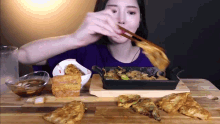 a woman is eating food with chopsticks from a pan on a table
