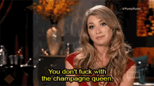 a woman in a red dress is saying you do n't fuck with the champagne queen
