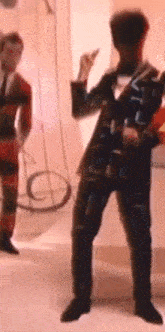 a man in a suit is dancing in a room with other people