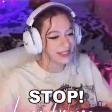 a girl wearing headphones and a t-shirt with the word stop written on it .
