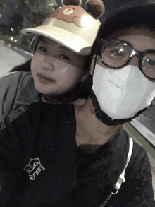 a man wearing a mask and a woman wearing a hat with teddy bear ears