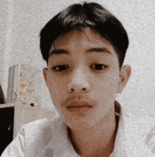 a young man with a mustache and a white shirt looks at the camera
