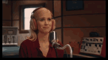 a woman wearing headphones and a red shirt is speaking into a microphone