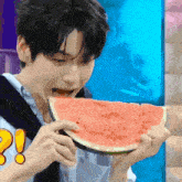 a young man is eating a slice of watermelon with an exclamation point on his shirt