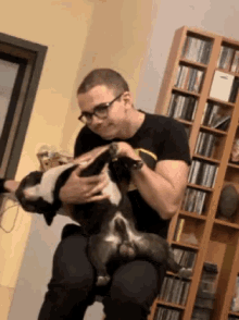 a man is holding a dog on his lap in front of a cd rack