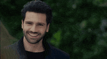 a man with a beard and a black shirt is looking at the camera