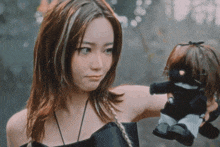 a woman in a black dress holds a black doll