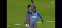 a soccer player wearing a blue jersey with the word bet on it is being congratulated by another player