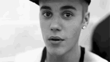 a black and white photo of justin bieber wearing a hat .