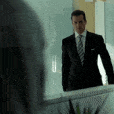 a man in a suit stands in front of a glass door