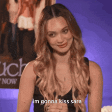a woman says i 'm gonna kiss sara in front of a movie poster
