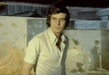 a man in a white shirt and tie stands in front of a sign that says ' a '