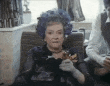 a woman wearing a blue hat is sitting in a chair holding a glass