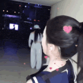 a woman with a heart in her hair is standing in a hallway