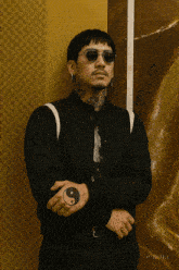 a man wearing sunglasses and a black jacket has a yin yang tattoo on his wrist
