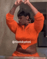 a woman in an orange crop top is looking at herself in a mirror