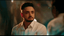 a man with a beard is looking at himself in a mirror