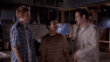 three men are standing next to each other in a room