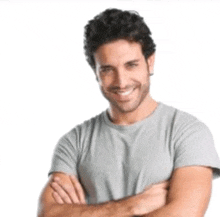 a man is smiling with his arms crossed and wearing a gray shirt .