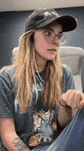 a woman wearing a hat and glasses is sitting down