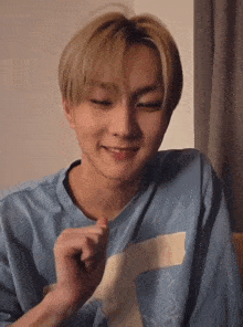 a young man wearing a blue shirt with a letter t on it