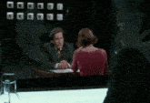 a man and a woman are sitting at a table talking to each other
