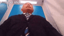 a man in a suit and tie is laying on a blue surface with his eyes closed .