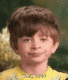 a young boy with a big haircut is smiling and making a funny face .