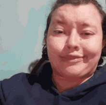 a woman in a blue hoodie is making a funny face and smiling .