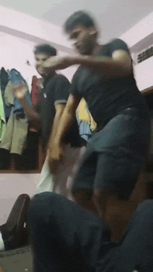 two men are dancing in a room with clothes hanging on the walls