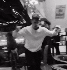 a man in a white shirt is dancing in a room with a sign that says budweiser on it