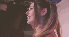 a close up of a woman 's face with a ponytail and a necklace .