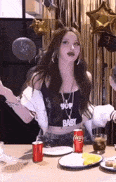 a woman is sitting at a table with plates , a can of coca cola and a glass of water .
