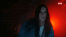 a woman with long hair is screaming in a dark room with red lights behind her .