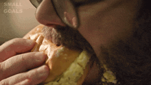 a man with a beard is eating a sandwich with the words small business goals on the bottom